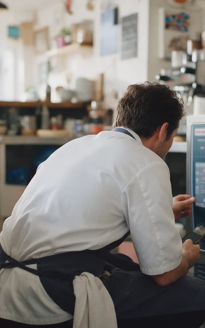 A chef crouching to check a combi oven that has stopped working